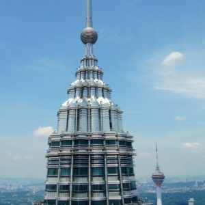 Spitze eines Petronas Towers und im Hintergrund der KL Tower